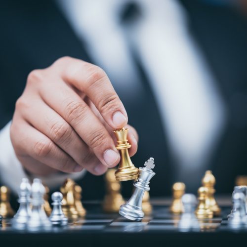 hand of businessman moving chess figure in competition success play